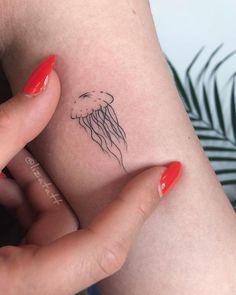 a woman's arm with a small tattoo of a jellyfish on her left side