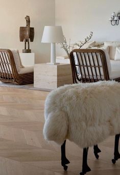 a white sheep standing on top of a hard wood floor next to a living room filled with furniture