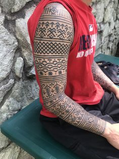 a man sitting on top of a green bench covered in tattoos