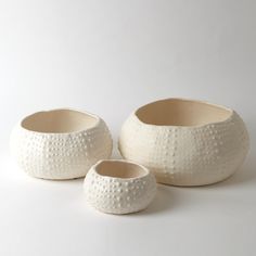 three white ceramic bowls with holes on them