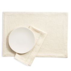 a white plate and napkin sitting on top of a place mat next to each other