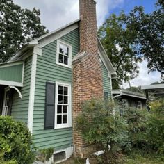 a small green house with a brick chimney