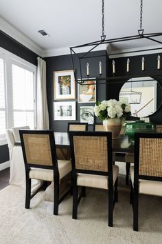 a dining room table with four chairs and a mirror on the wall in front of it