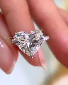 a heart shaped diamond is being held by someone's hand