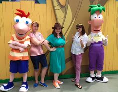 three women and one man standing in front of a cartoon character