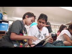 two young boys sitting on the floor looking at a book