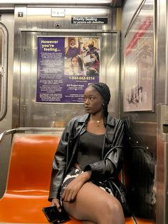 a woman sitting on an orange bench in a subway car with her legs crossed and looking off to the side