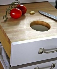 two tomatoes and a knife on a cutting board next to an open drawer with drawers