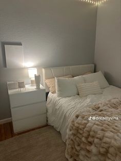 a bedroom with a bed, dresser and lamp