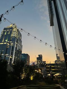 the city skyline is lit up at night with lights strung from it's sides