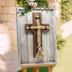 a wooden cross decorated with flowers and rope