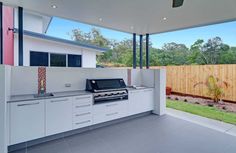 an outdoor kitchen with white cabinets and stainless steel counter tops is seen from the outside