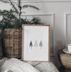 a christmas tree is displayed in a frame next to a basket with a cup on it