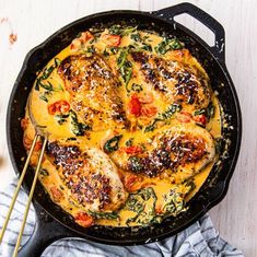 a skillet filled with chicken covered in cheese and vegetables