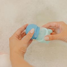 a woman's hand is holding a baby bottle in the bathtub with foam on it