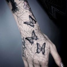 a woman's hand with butterflies on it and spider webs in the background