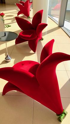 three red chairs sitting on top of a tiled floor