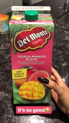 a carton of del monte guava mango blend sitting on a counter top next to a hand holding a black pen