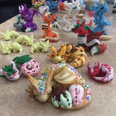 there are many different toy animals on the table together, including doughnuts and dragon figurines