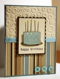 a birthday card with a blue cake on it and two buttons attached to the front