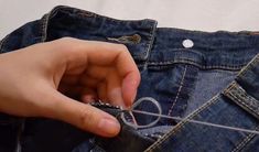 someone is sewing something on the back of their jean pants with a pair of scissors