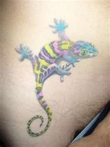 a colorful lizard tattoo on the back of a man's stomach, with blue and yellow stripes