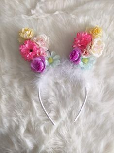 a pair of ears with flowers on them sitting on top of a white fur surface