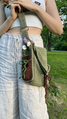 a woman wearing white pants holding a crocheted purse