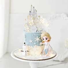 a frozen princess cake on a plate with snowflakes around it and a castle in the background