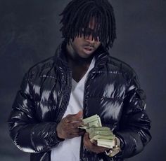 a man with dreadlocks holding money in one hand and wearing a black jacket