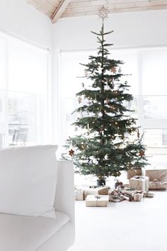 a living room with a christmas tree in the corner and presents on the floor next to it