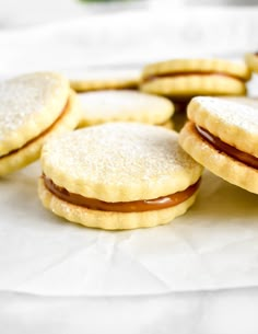 some cookies with jam on them sitting on top of a white table cloth next to each other