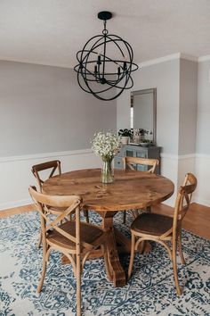 a dining room table with four chairs and a chandelier hanging from the ceiling