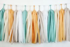 several tassels hanging from a line on a white wall in different colors and sizes