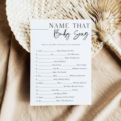 a name that baby song is on top of a white card next to a straw hat