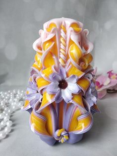 a yellow and purple vase sitting on top of a table next to pearls, beads and flowers