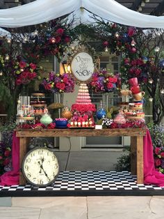 a table topped with lots of cake next to a clock