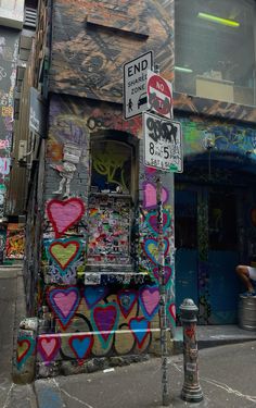 a building with lots of graffiti on it's side and street signs in front