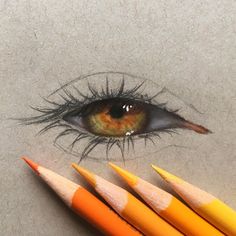 three pencils in front of an eye with the bottom one colored orange and the other yellow