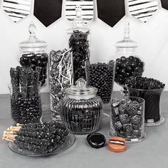 black and white candies are arranged in glass containers on a table with other candies