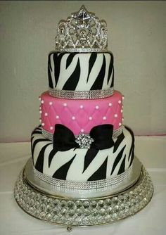 a three tiered cake decorated with zebra print and a tiara