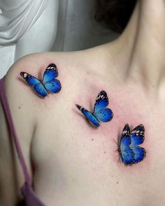 three blue butterflies on the back of a woman's shoulder and upper chest,