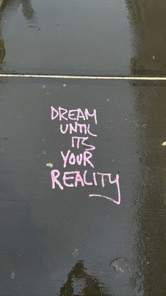 graffiti written on the ground in front of a parking meter that says dream until it's your reality