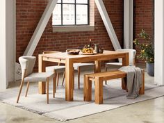 a dining room table with two chairs and a bench in front of a brick wall