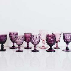 a group of wine glasses sitting on top of a white table next to each other