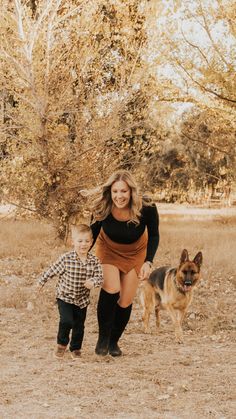 a woman and her son are running through the field with their dog in tow during an outdoor family photo session