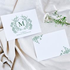 two cards with the letter m on them are laying next to some flowers and leaves