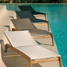 three lounge chairs sitting on the edge of a swimming pool