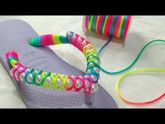 a pair of flip flops with colorful beads on them next to a spool of thread