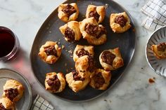 several pastries on a plate next to a cup of tea and a glass of wine